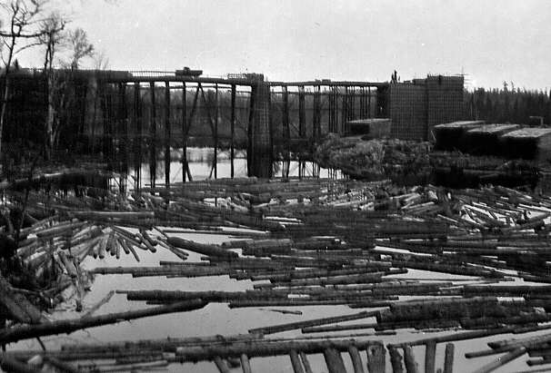 Pont de la rivière Camatose sur la route Senneterre et, en avant-plan, des billots de bois (pitounes) flottant sur la rivière à Mont-Laurier dans le comté de Ponctiac en 1947