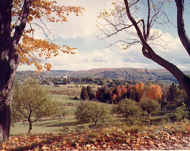 En 1970, paysage des Cantons de l'Est, des environs (en automne) et village au loin 