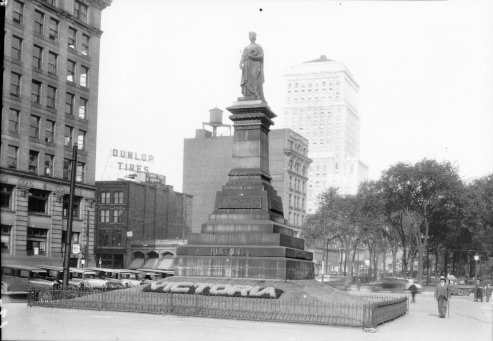 Le monument Victoria situé au square Victoria: on y aperçoit à l'arrière-plan l'édifice de la Bell Telephone Co., ainsi qu'un panneau-réclame de Revelation Havana Cigar