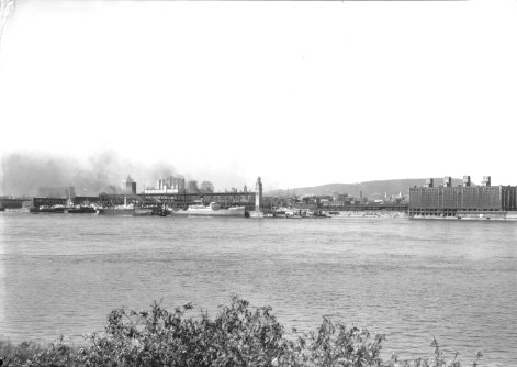 Le port de Montréal, à partir de l'île Ste-Hélène dans les années 1930: on y voit le fleuve St-Laurent, l'entrepôt frigorifique, la tour de l'horloge, l'élévateur de grains numéro 2 et le mont Royal en arrière-plan