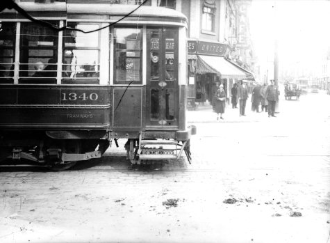 Un tramway arrivant à l'angle des rues St-Laurent et Ontario Est dans les années 1920: on aperçoit un commerce United Cigars Store et l'enseigne commerciale du Strathcona Café